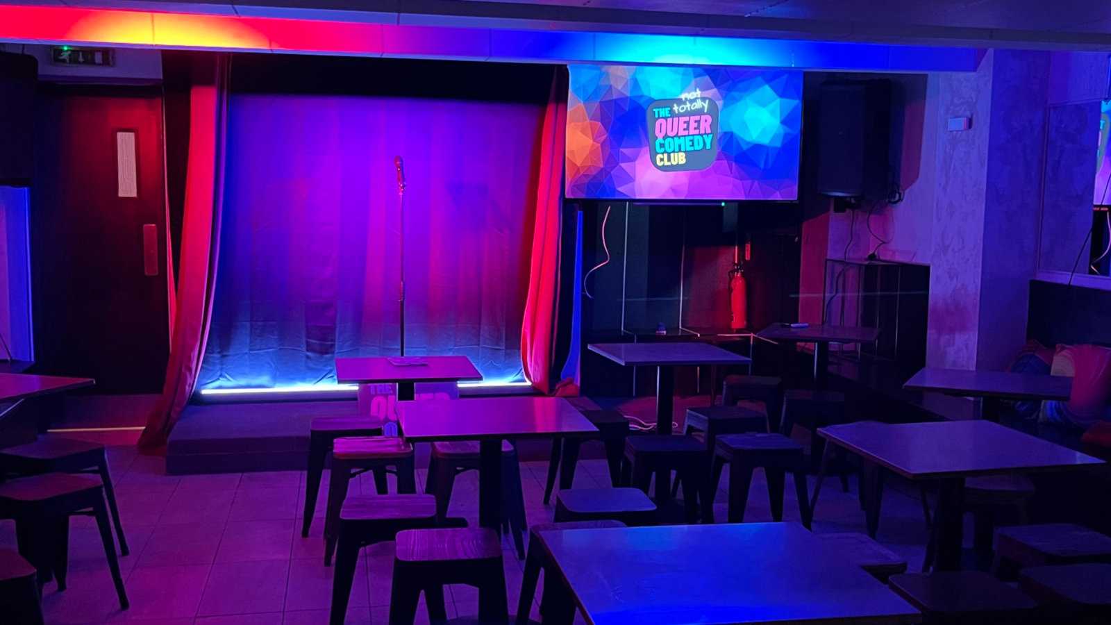 An empty stage at the Queer Comedy Club in London all lit up and ready to fill up with an audience and performers.