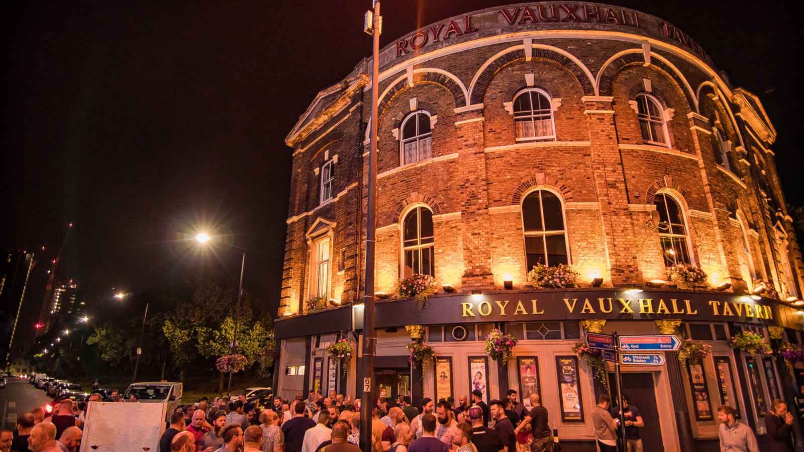 The exterior of the Royal Vauxhall Tavern in London at night, lit up and surrounded by people.