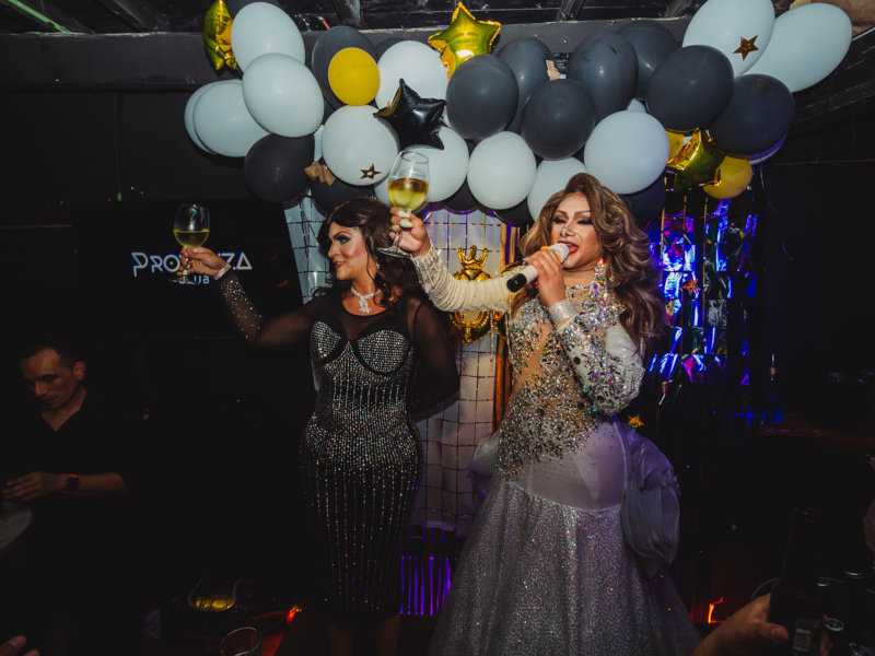 Two elegant drag queens singing in front of balloons at the Provence gay club in Playa del Carmen.