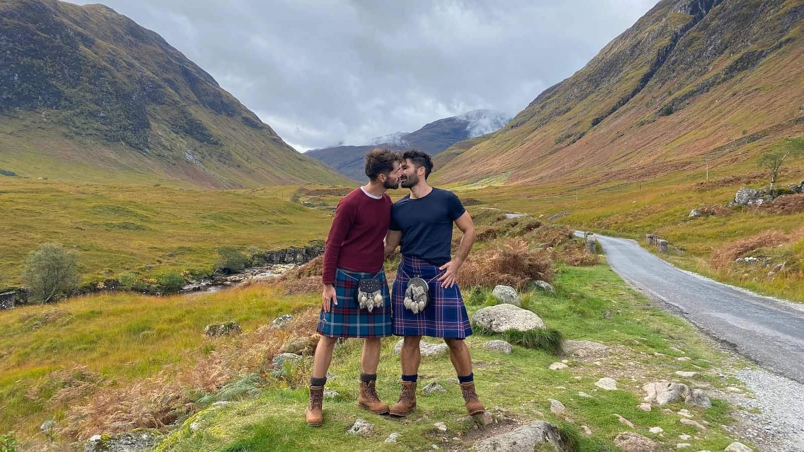 Gay couple kiss in kilts on Skyfall Road in Glencoe, Scotland.