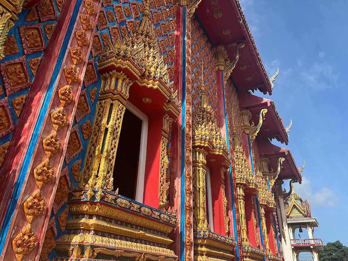The exterior of a colorful Thai temple in Phuket on a sunny day.