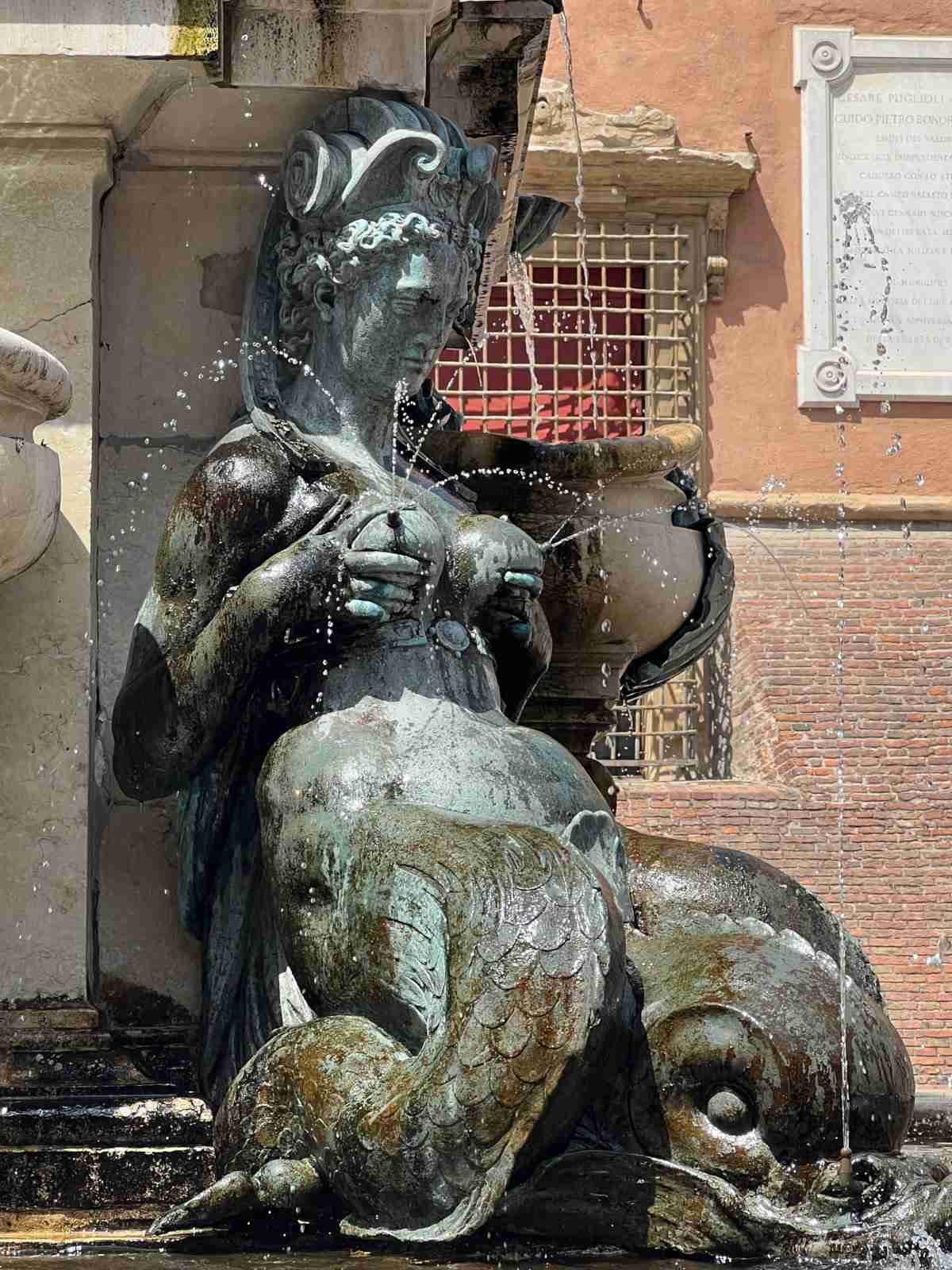 A statue fountain of a woman with large breasts spraying water.