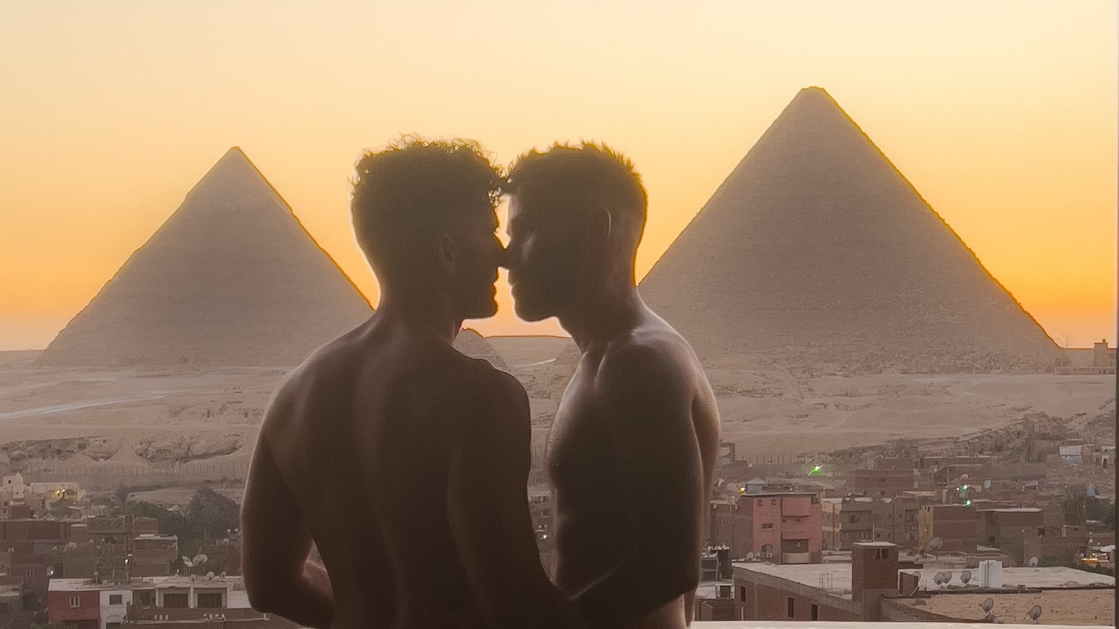 Gay couple kissing in front of Giza pyramids in Egypt.