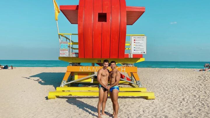 Gay couple Stefan and Seby posing on the gay beach of Miami Beach for Pride.