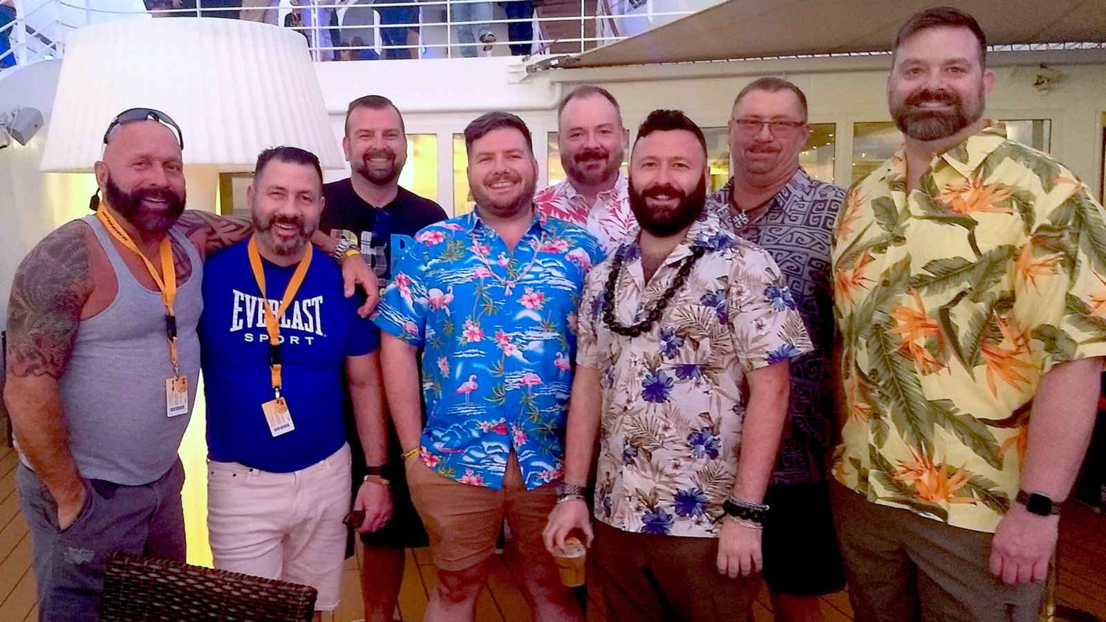 A group of 8 guys posing for a photo together on a cruise ship.