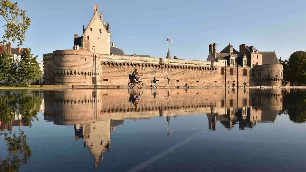 A French chateaux with its reflection in still water in front of it.