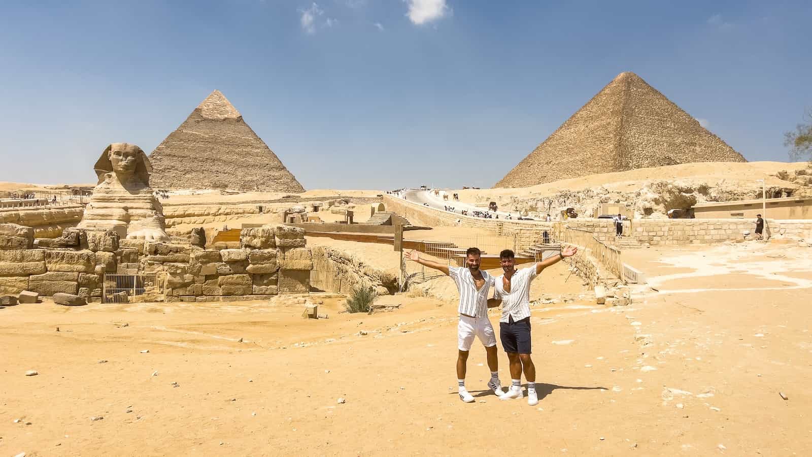 Gay couple outside of the Sphinx statue and pyramids of Giza in Egypt.