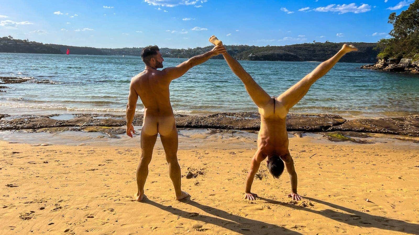 Gay couple naked handstands at Cobblers gay beach in Sydney.