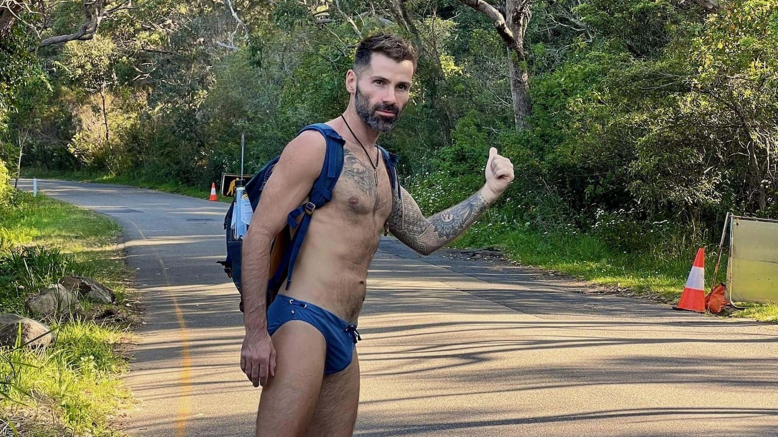 Seby in Speedos hitchhiking to Sydney gay beaches.