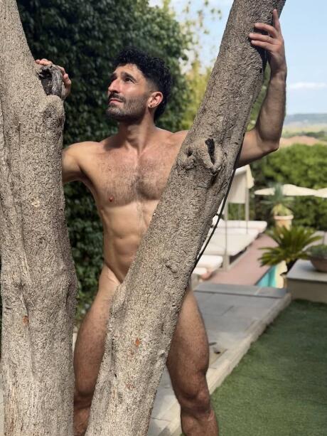 Stefan naked behind a tree in the villa of The Naked French Experience.