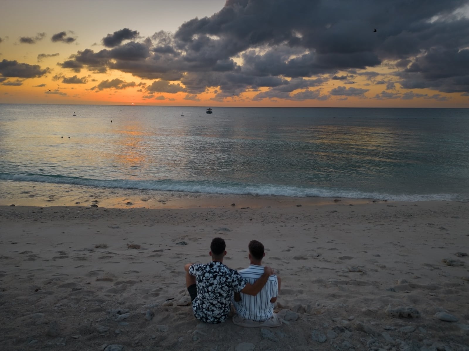 Gay couple watching the sunset on Lady Elliot Island beach.
