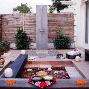 A courtyard with a shower and a plunge pool filled with flower petals.