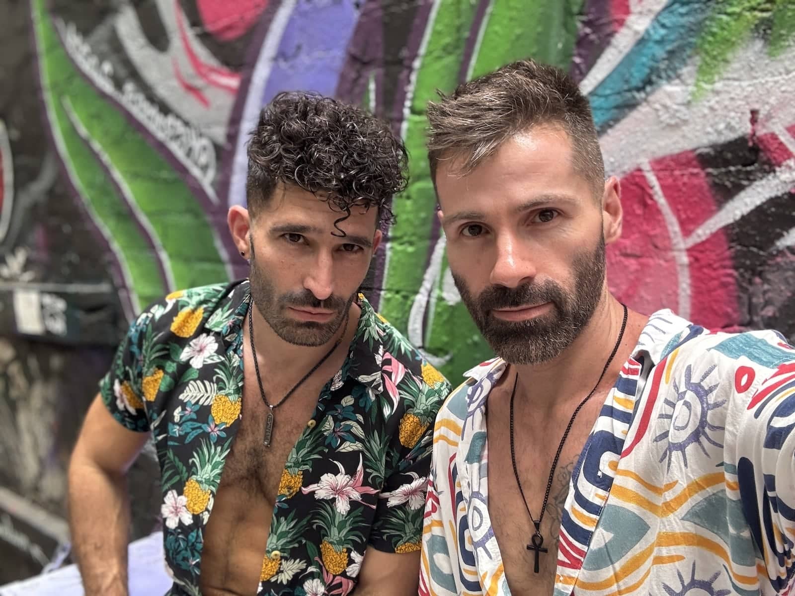 Gay couple posing in front of colorful Melbourne street art.