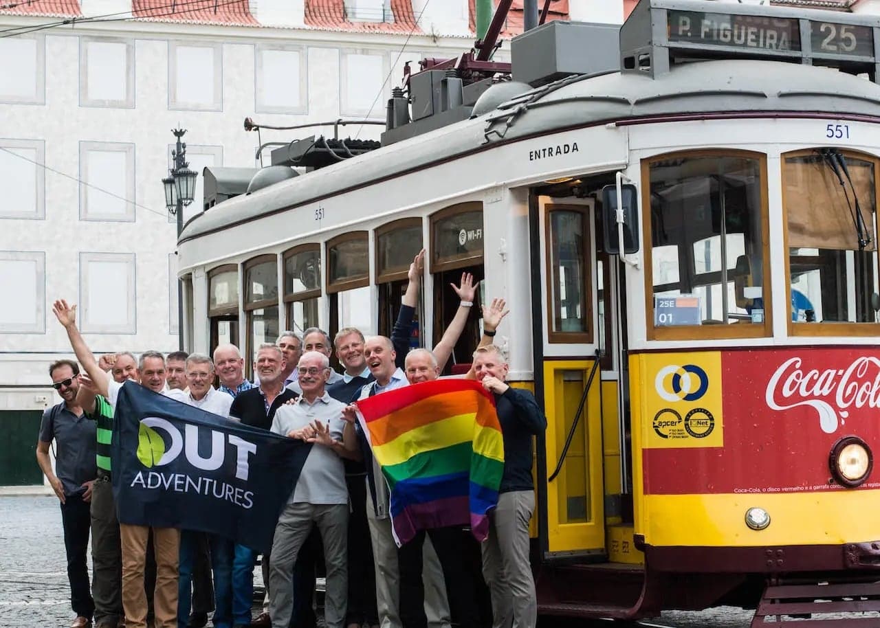 Outadventures gay tour in Portugal with gay group and rainbow flag in front of Lisbon tram.