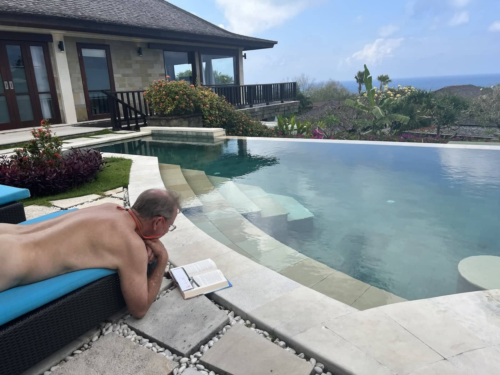 Naked man relaxing by the book at the Naked Paradise Villa pool in Bali.