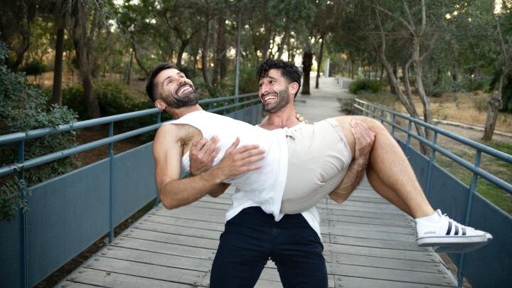 Gay couple embracing, Stefan carrying Seby and laughing.