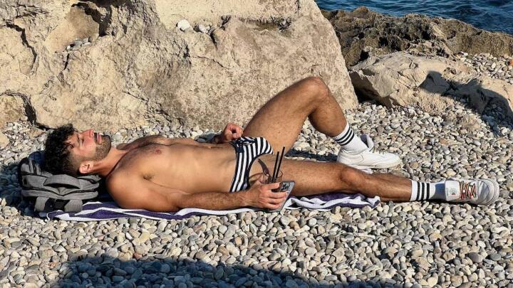 Gay guy in Speedos resting at the Kotor Beach in Croatia.