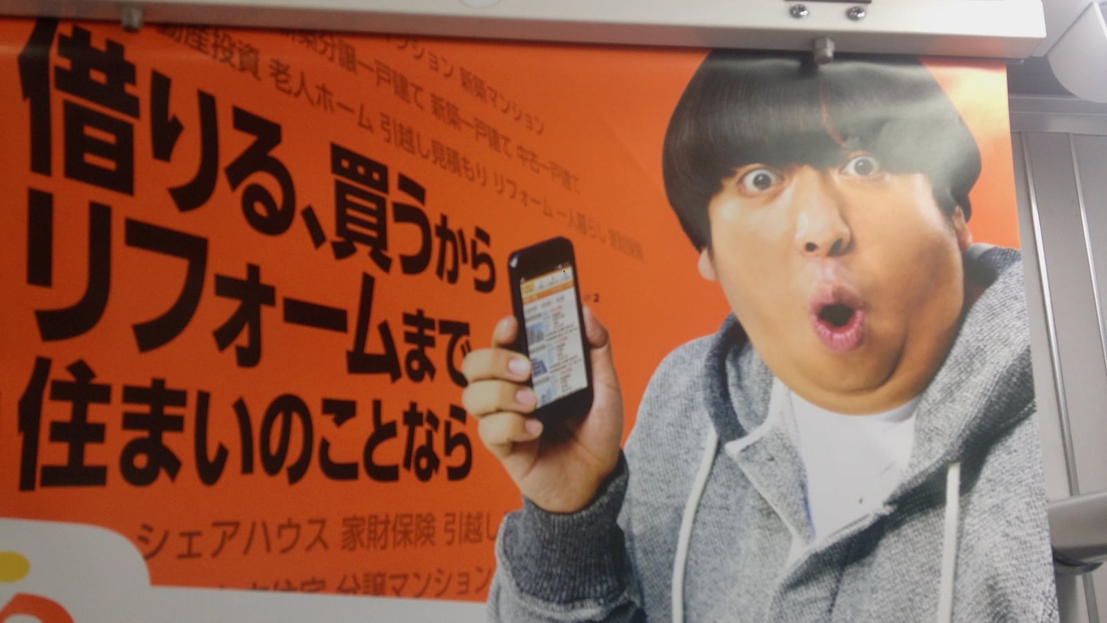 Gay advert in Tokyo Japanese man holding phone with shocked expression.