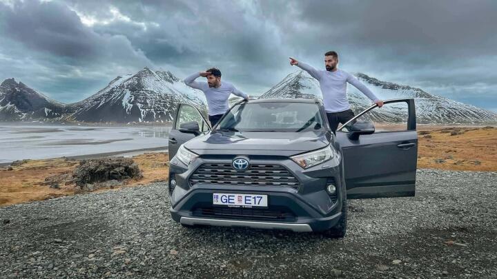 Gay couple leaning out of car chasing the Northern Lights on Iceland Ring Road.