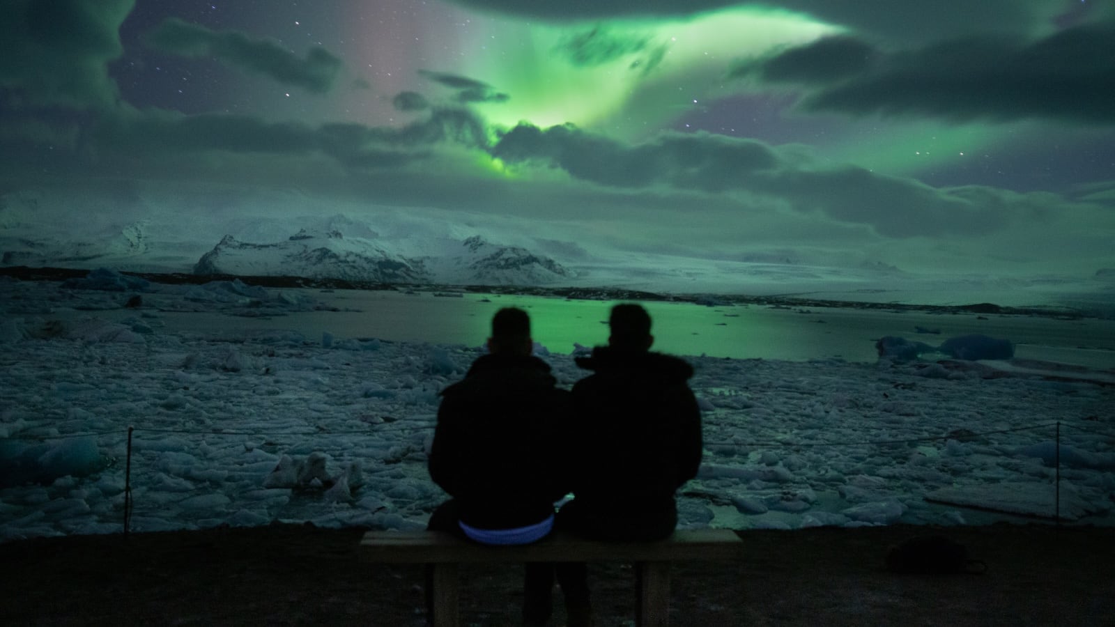 Gay couple watching the Northern Lights together at Diamond Beach in Iceland.