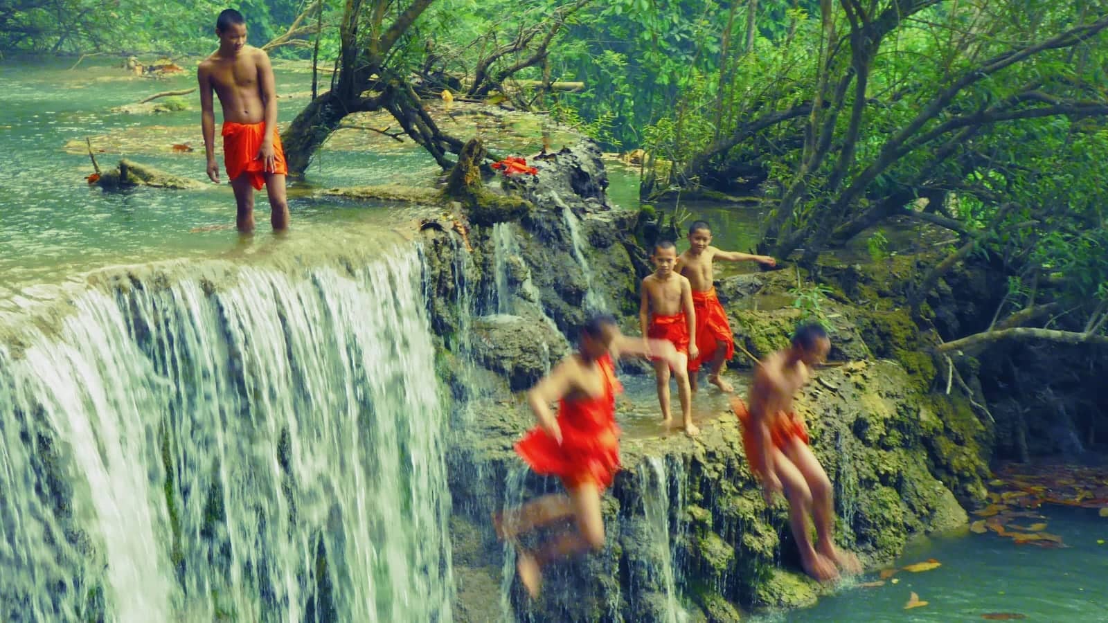 Monks diving into Kiuang Si Falls in Luang Prabang in Laos.