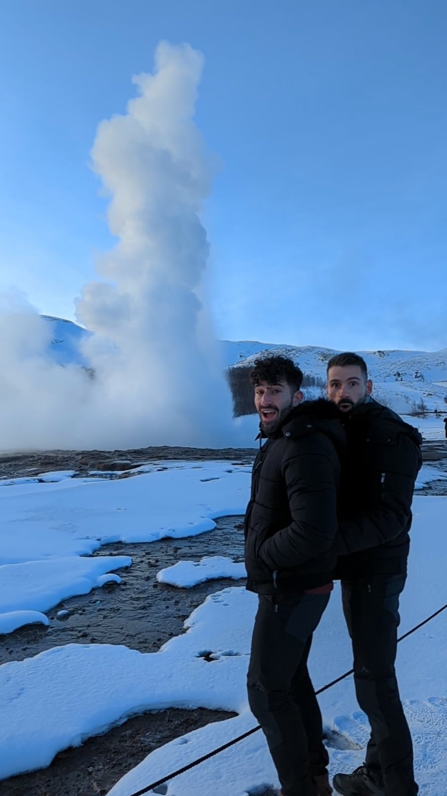 Gay couple watching the Strokkur Geysir at the Geothermal Area.