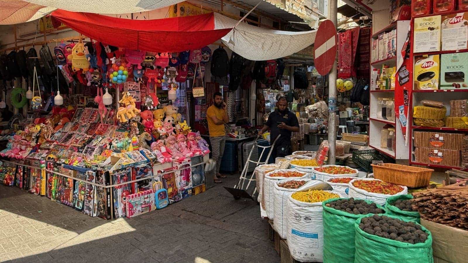 A couple of men standing in a market of brightly coloures goods