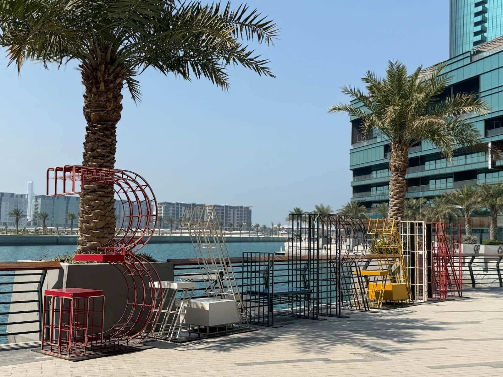 The word Bahrain spelled in metal letters next to water on a sunny day.