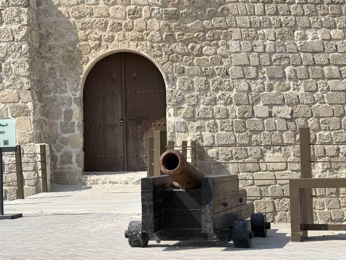 A canon in front of a stone structure.