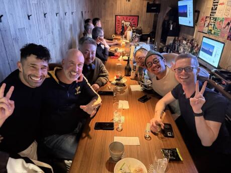 Stefan and a bunch of friends posing for a photo together at a long table in a bar.