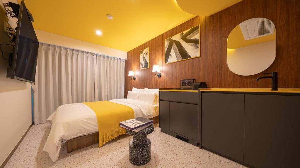 A cosy hotel room with bright yellow accents at the Nouvelle Hotel in Seoul.