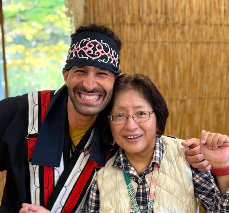 Stefan in traditional Ainu clothing smiling with a woman in regular clothing.