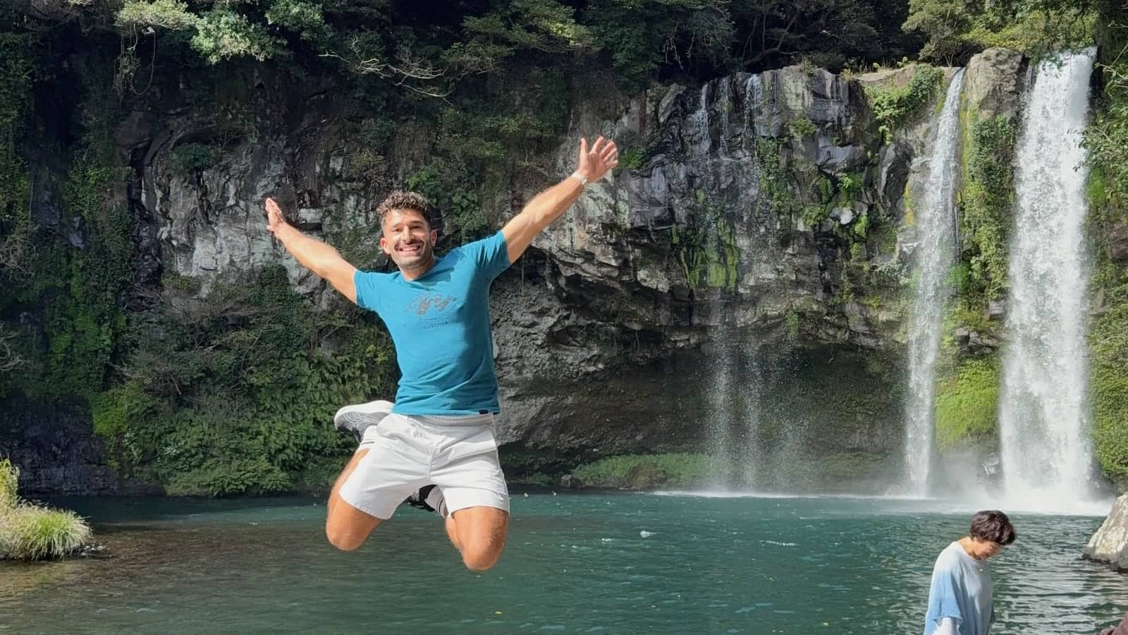 Stefan leaping for joy in front of a beautiful waterfall.