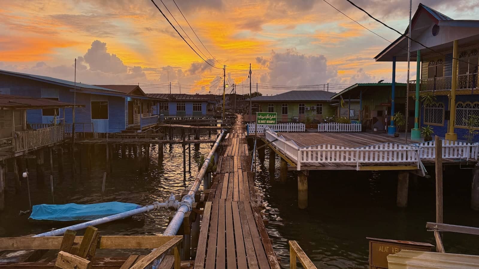 Houses in stilts and wooden platforms above water at sunset.