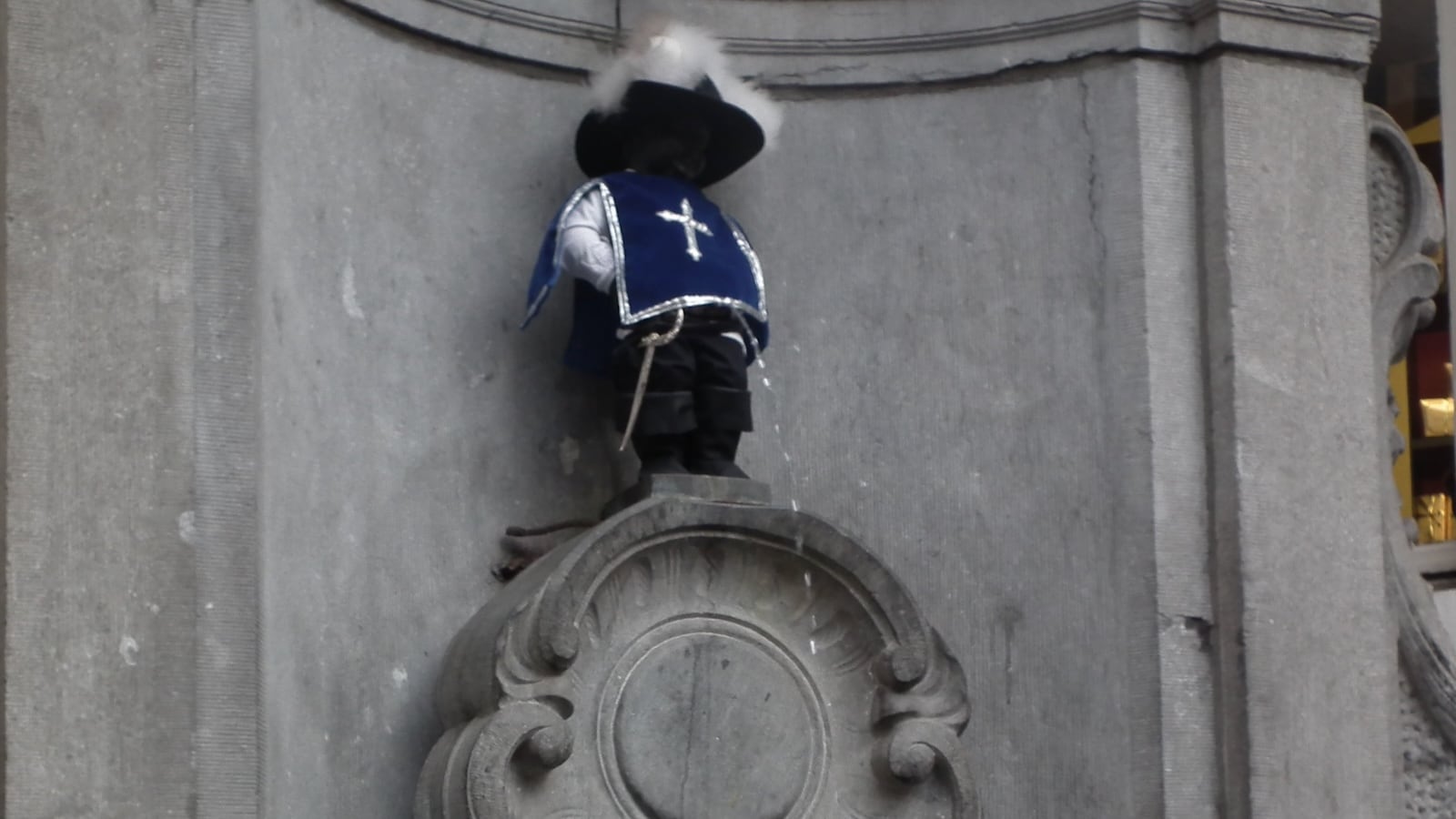 The peeing child fountain statue in Brussels known as Manneken Pis, dressed up like a musketeer.