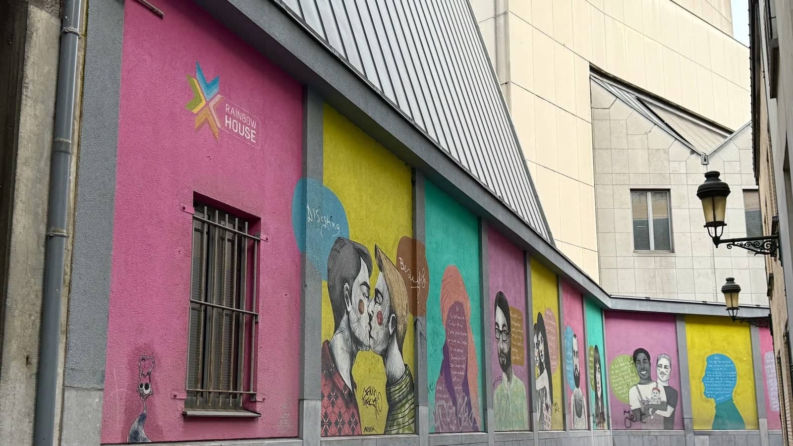 The exterior of Rainbow House in Brussels, with brightly painted walls and mural art.