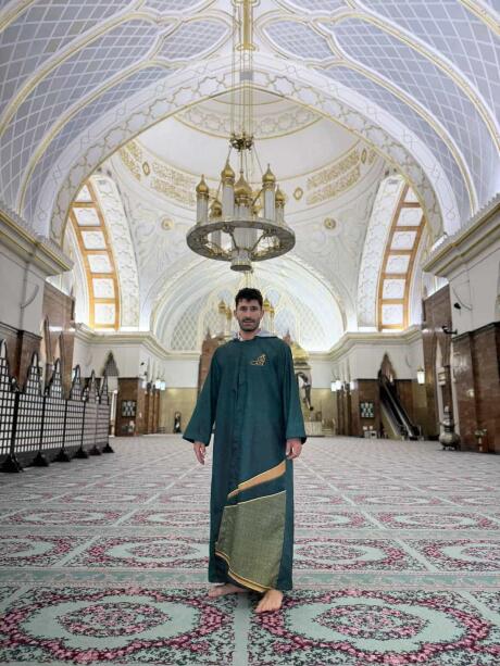 Stefan wearing traditional Brunei robes inside a beautiful mosque with tiled floors.