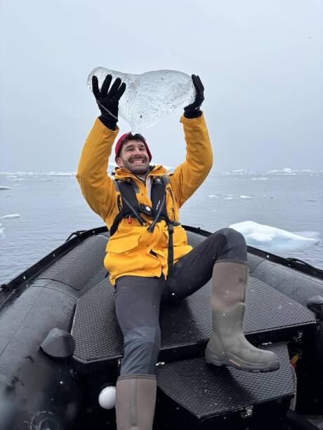 Stefan holding up an Antarctic iceberg on a zodiac boat.