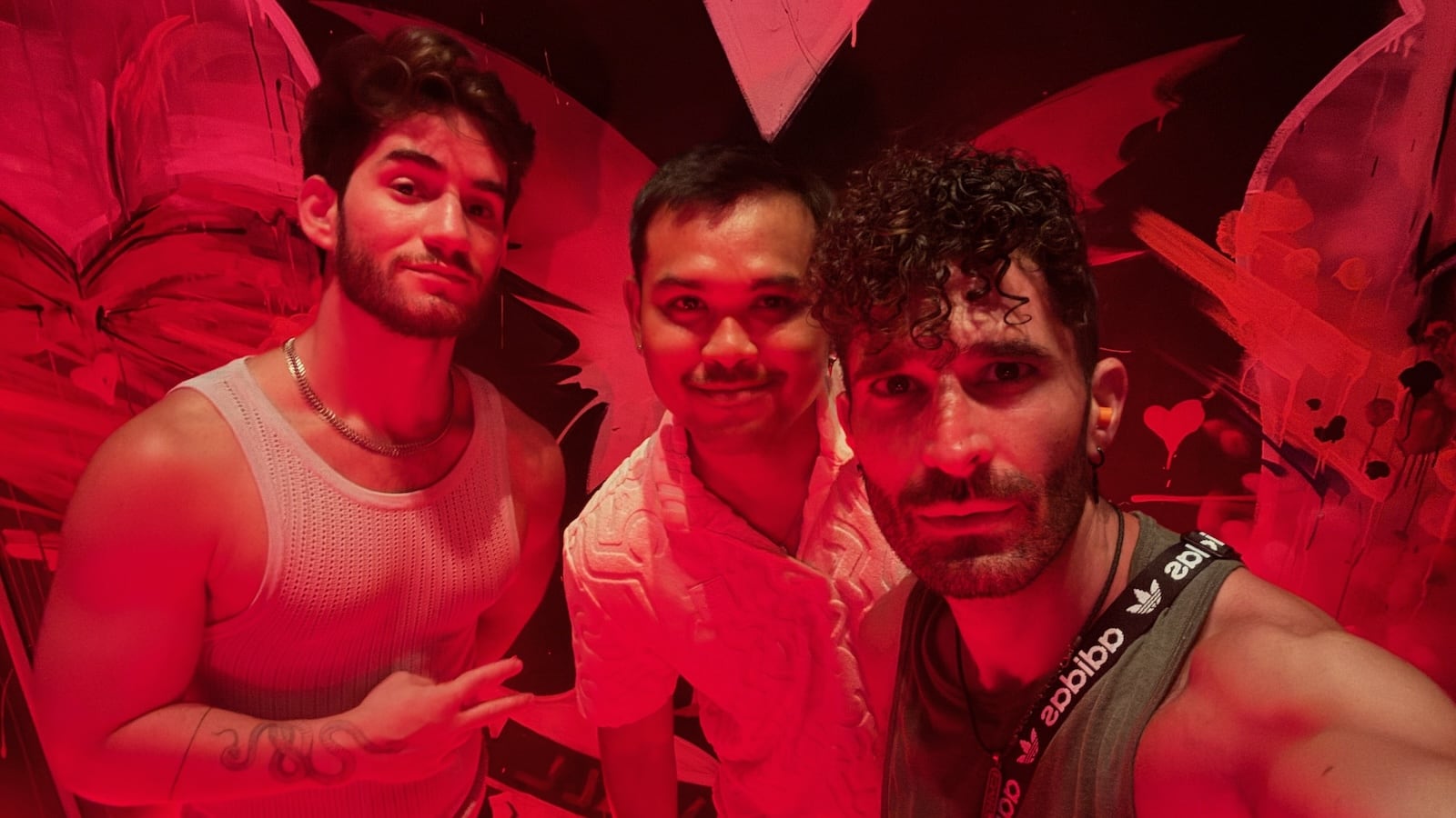 Stefan and two friends posing in a club lit up with red lights.