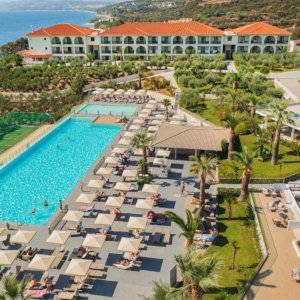 An aerial view of a hotel pool surrounded by loungers with the main building in the background.