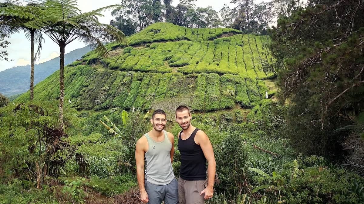 Stefan and Seby smiling together in front of a lush green hill.