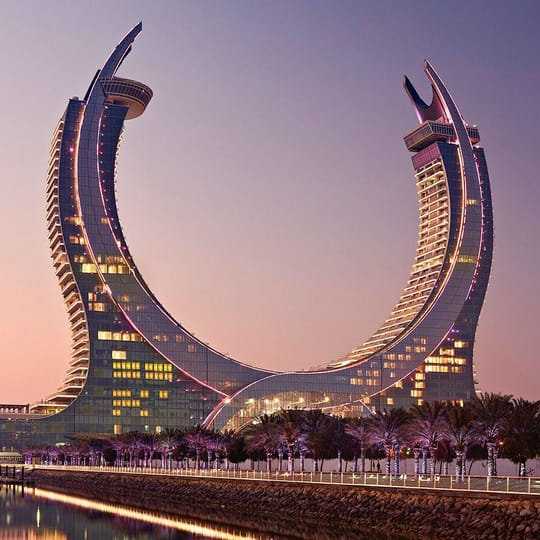 A horseshoe shaped building with lights on at dusk.