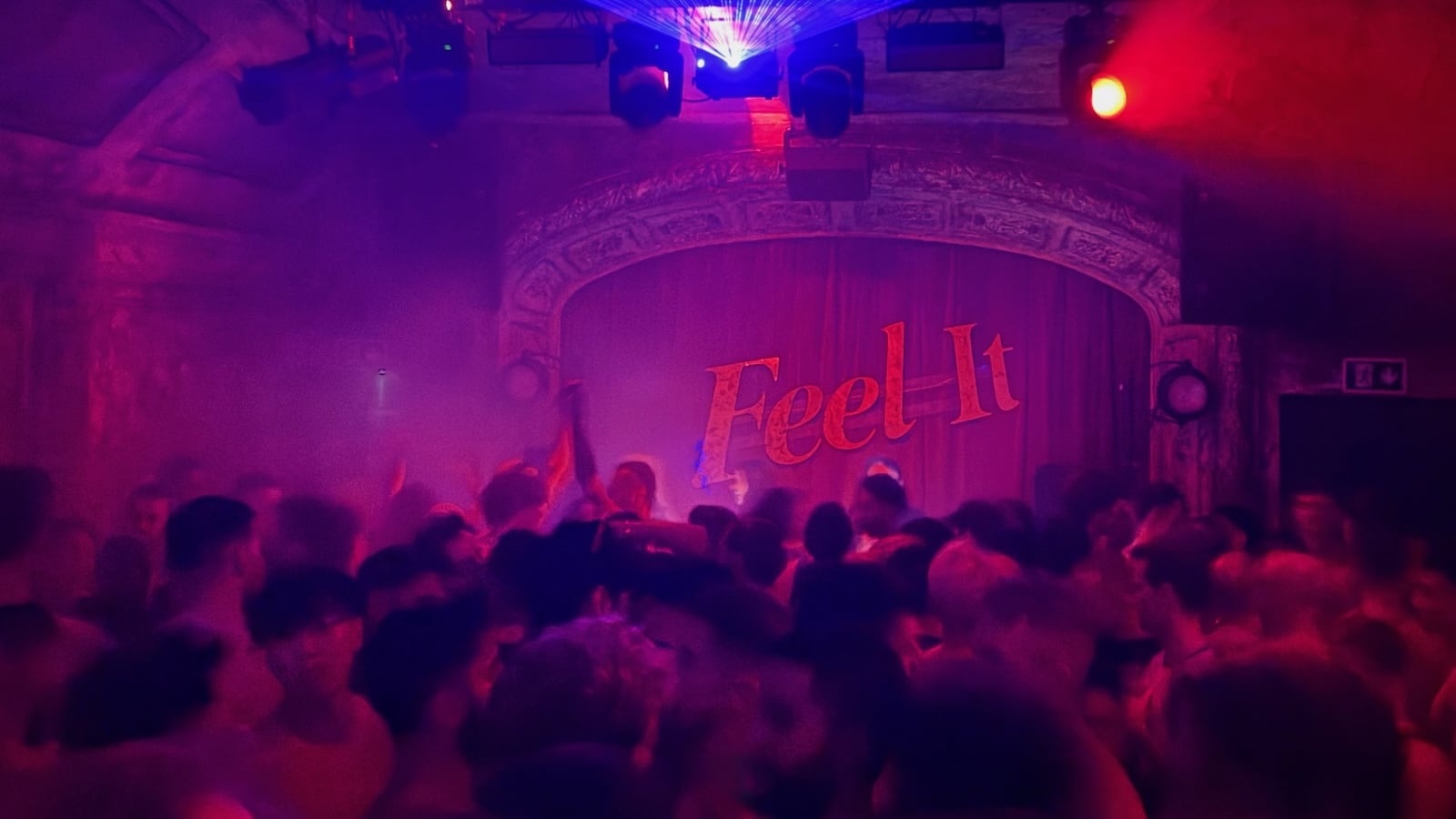 A blurry dance floor at a club with the words "feel it" on the wall.