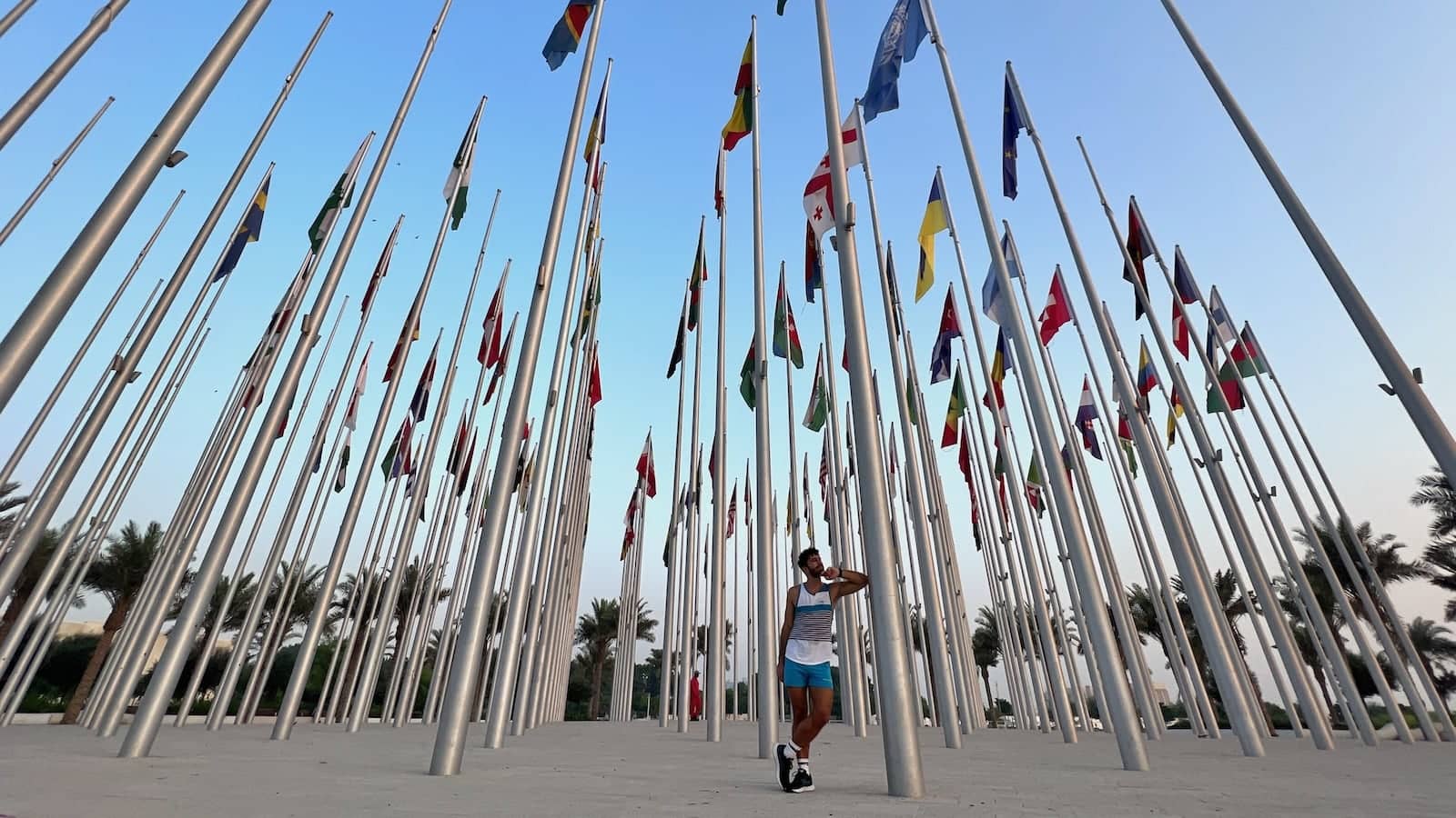 Stefan leaning against a flagpole surrounded by many more flagpoles.