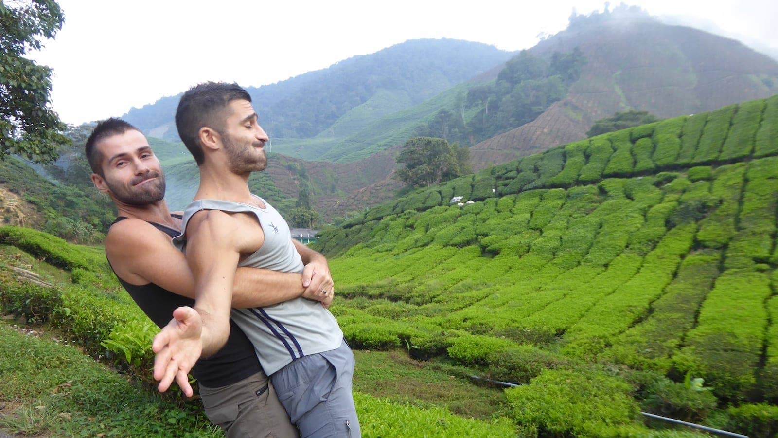 Seby picking up Stefan from behind in front of a lush green landscape.