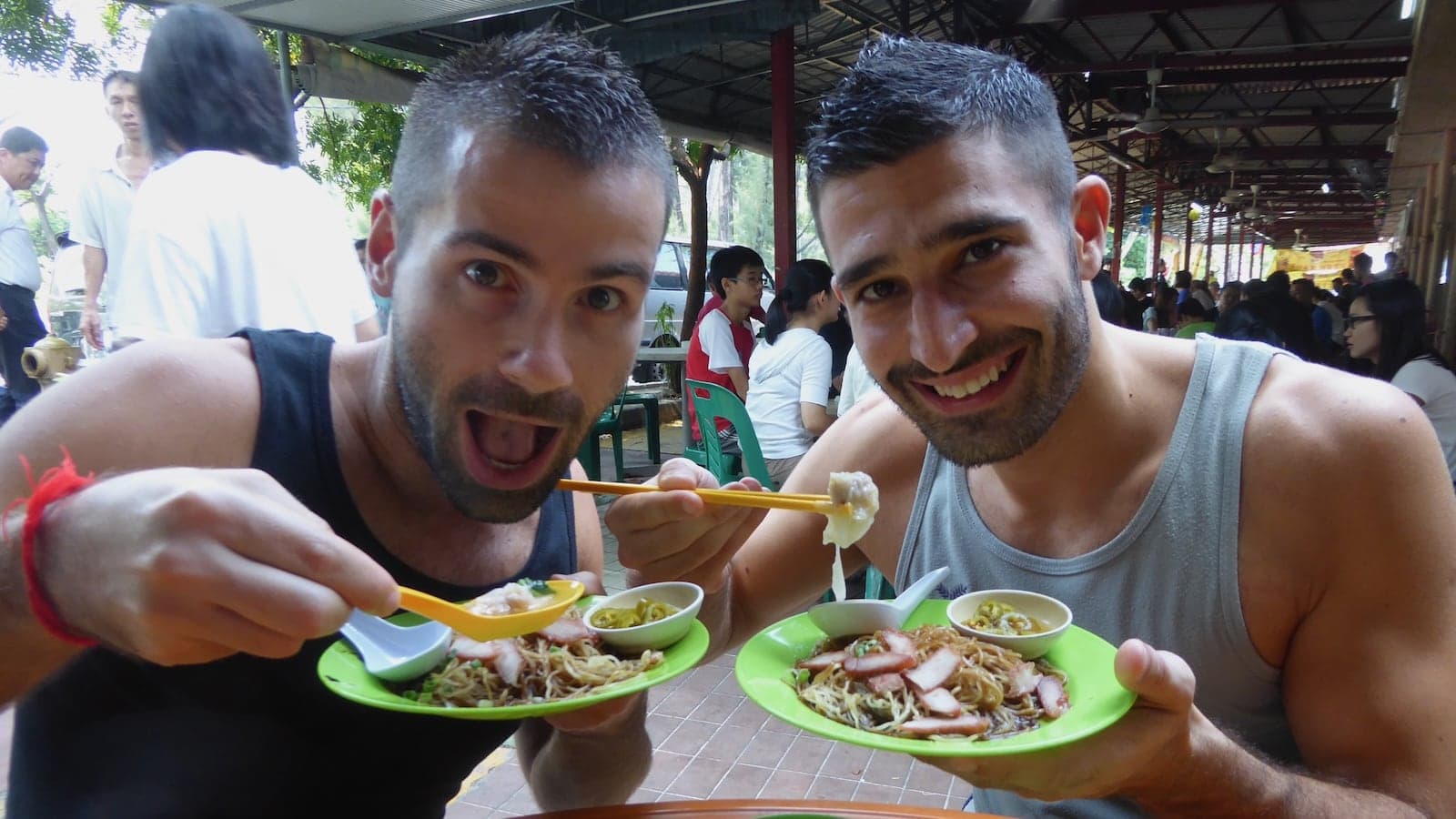 A close up of Seby and Stefan about to eat from plates of food in a market.