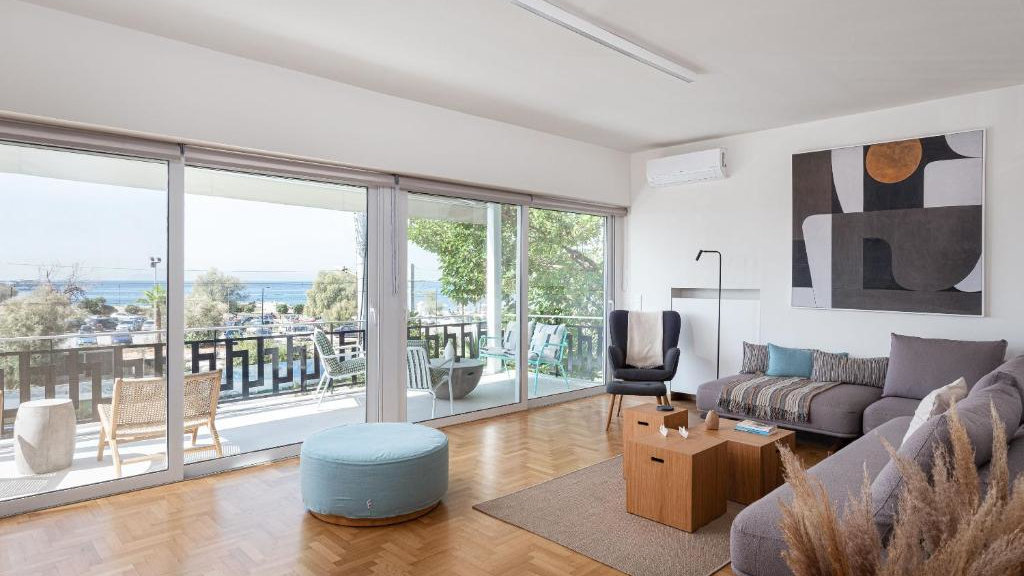 A spacious living room with modern decor and a big balcony looking towards ocean.