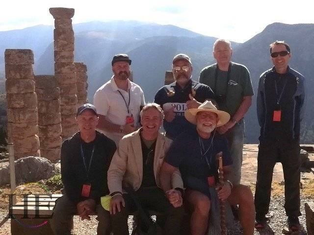 A group of men sitting amongst some ancient ruins on a hill.