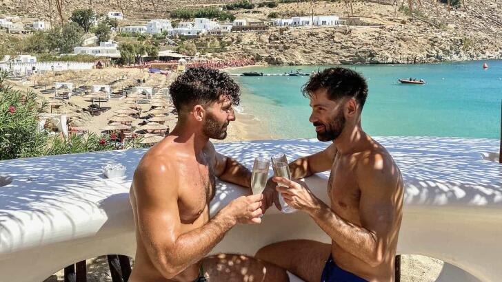 Gay couple Stefan and Seby enjoying a cocktail at the Jackie O gay beach bar in Mykonos.