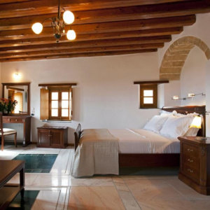 A cosy hotel room with whitewashed stone and wooden beams.